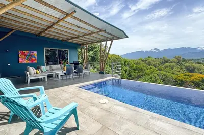 a villa with a swimming pool and blue chairs at Secret Mountain Top 3BR Casa Colibrí private pool in Quepos