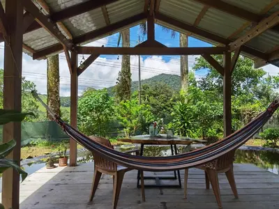a hammock on a screened in porch with a table and a view at Greenhouse Lofts Miravalles in Aguas Claras