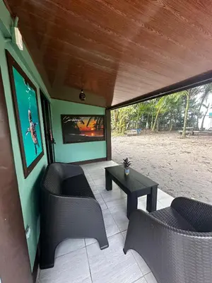 a screened in porch with two chairs and a table at Caribbean View House in Tortuguero