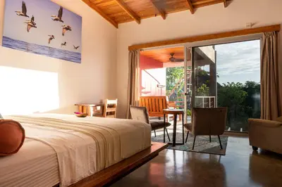 a bedroom with a bed and a sliding glass door at Iluminar Beachfront Suites in Nosara