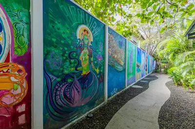 a wall covered in colorful graffiti next to a sidewalk at Iluminar Beachfront Suites in Nosara