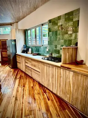 a large kitchen with wooden floors and a refrigerator at Iluminar Beachfront Suites in Nosara