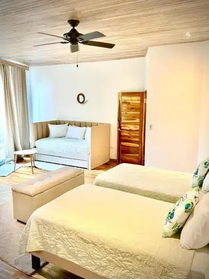 a bedroom with two beds and a ceiling fan at Iluminar Beachfront Suites in Nosara