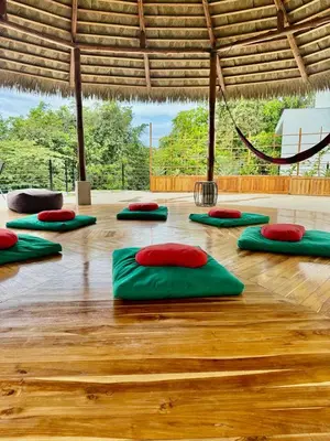 a room with green and red pillows on a wooden floor at Iluminar Beachfront Suites in Nosara