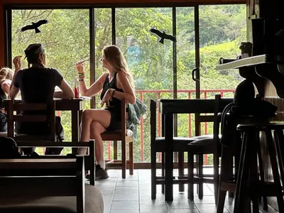 two people sitting at a table in a room with a window at Monteverde Monkey Hostel in Monteverde Costa Rica