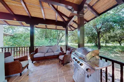 a screened in porch with a stove and chairs at Pinilla Flor de Malinche 15 in Tamarindo