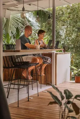 two people sitting at a bar with their laptops at Cuatro Vientos Lodge & Apartments - Santa Teresa, CR in Santa Teresa Beach