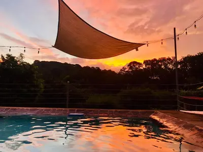 a pool with a sunset in the background at Bamboo River House and Hotel in Dominical