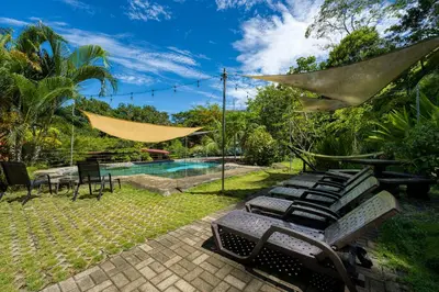 a backyard with a pool and chairs and a hammock at Bamboo River House and Hotel in Dominical