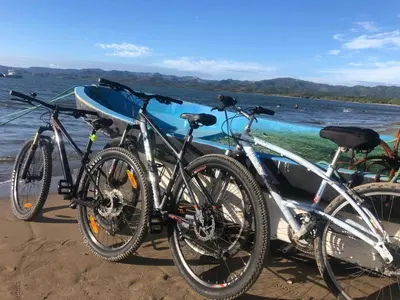 three bikes parked on the beach next to a boat at Cabañas Casa Soley in Puerto Soley