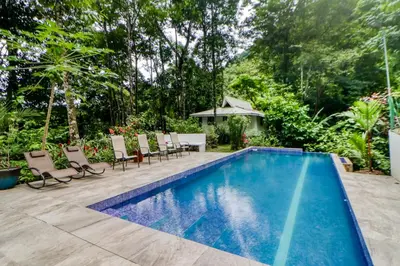 a swimming pool in a yard with chairs and a table at Lost Pools Bungalow at Sloth in Uvita