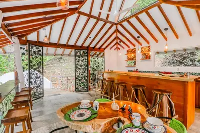 a kitchen with a wooden table and a bar at Lost Pools Bungalow at Sloth in Uvita