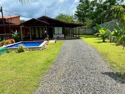 a house with a swimming pool in front of a yard at La Cabaña de Merce in Tanque