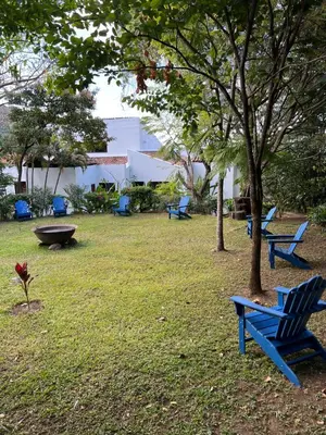a park with blue chairs and a tree at Hotel Don Ernesto By La Chimba in San José