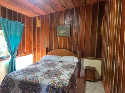 a bedroom with a bed in a room with wooden walls at Cabaña Rana Verde in Monteverde Costa Rica