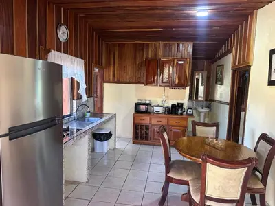 a kitchen with a table and a stainless steel refrigerator at Cabaña Rana Verde in Monteverde Costa Rica