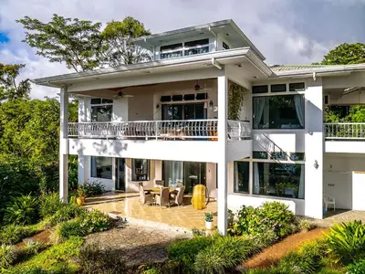 a large white house with a balcony at Villa Corazón - private beach at Lake Arenal in Nuevo Arenal