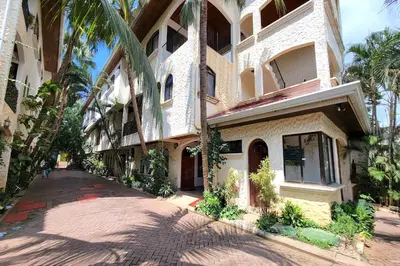 a large building with palm trees next to a street at LA BUENA VIDA CONDO in Tamarindo