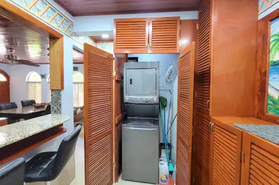 a kitchen with a refrigerator and a kitchen with wooden cabinets at LA BUENA VIDA CONDO in Tamarindo