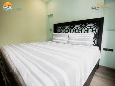 a large white bed with white sheets and striped pillows at Palo Rosa in Quepos