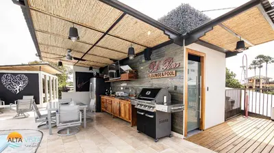 an outdoor kitchen with a grill and a table and chairs at Palo Rosa in Quepos