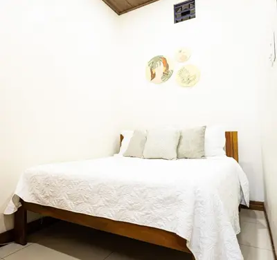 a white bedroom with a bed with white sheets at Palo Rosa in Quepos