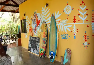 a group of surfboards on a wall with paintings at Luminosa Uvita Hostel in Uvita