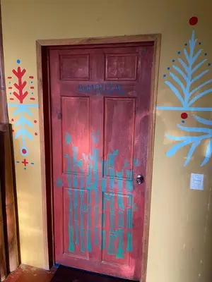 a red door with a sign on a wall at Luminosa Uvita Hostel in Uvita