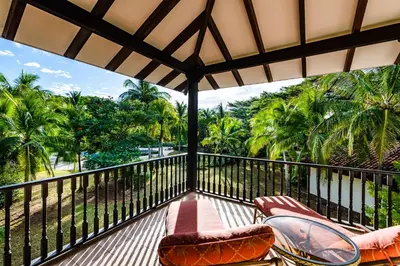 a balcony with chairs and a view of palm trees at Villa Estrella del Mar in Tamarindo
