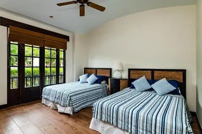 a bedroom with two beds and a ceiling fan at Villa Estrella del Mar in Tamarindo