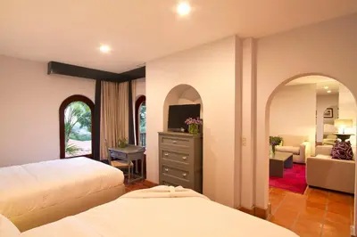 a bedroom with two beds and a living room at Alta Las Palomas Hotel in San José