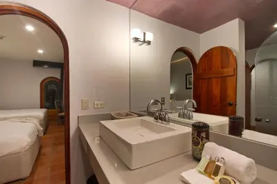 a bathroom with a large white sink and a bed at Alta Las Palomas Hotel in San José