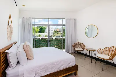 a bedroom with a bed and a large window at Sea La Vie Suites - By The Beach in Tamarindo