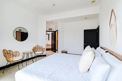 a bedroom with a large white bed and chairs at Sea La Vie Suites - By The Beach in Tamarindo