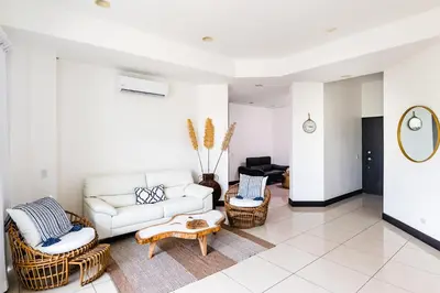 a living room with a white couch and wicker chairs at Sea La Vie Suites - By The Beach in Tamarindo