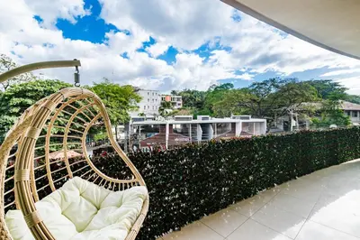 a rattan chair sitting on a patio next to a hedge at Sea La Vie Suites - By The Beach in Tamarindo