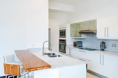 a kitchen with white cabinets and a wooden counter top at Sea La Vie Suites - By The Beach in Tamarindo