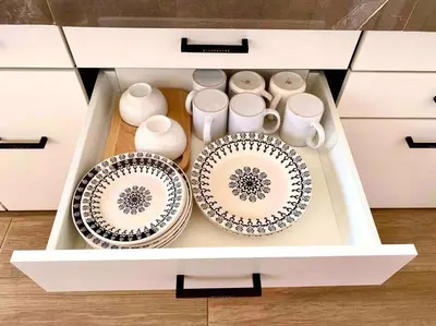 two plates and cups in a white cabinet at Hoja Azul Loft Guanacaste in Hojancha