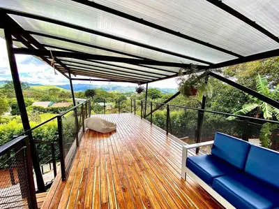 a deck with a blue couch and a view of the mountains at Hoja Azul Loft Guanacaste in Hojancha