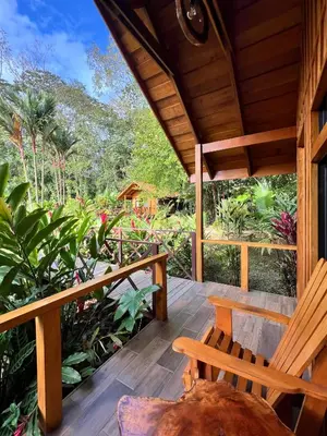 a porch of a house with a bench and plants at La Fortuna Natural Green in Fortuna