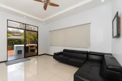 a living room with a black leather couch and a white wall at Playa Tamarindo, CasaMar de Tamarindo in Tamarindo