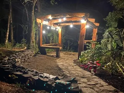 a wooden pergola with a stone pathway at night at Casitas del Bosque Monteverde. in Monteverde Costa Rica