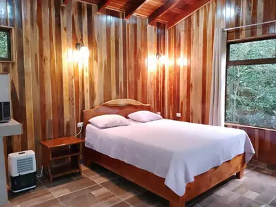 a bedroom with a bed in a wooden wall at Casitas del Bosque Monteverde. in Monteverde Costa Rica