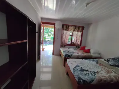 a bedroom with two beds and a door to a yard at Cabañas Daneysha in Tortuguero