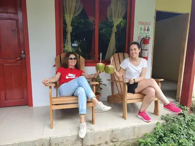 two women sitting in chairs on the porch of a house at Cabañas Daneysha in Tortuguero