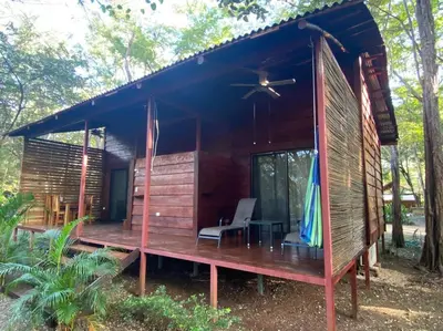 a cabin in the woods with a porch and a chair at Casa Natural Madera in Brasilito