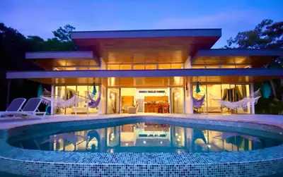 a house with a swimming pool in front of it at Casa de Teak in Savegre