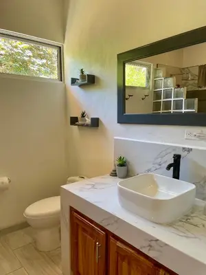 a bathroom with a sink and a toilet and a mirror at Casa de Teak in Savegre