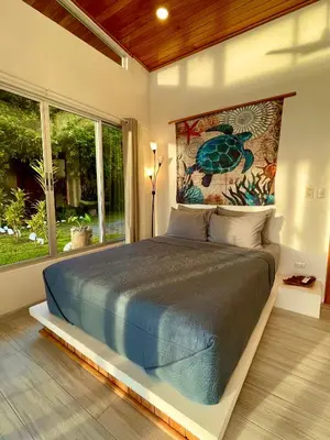 a bedroom with a bed and a large window at Casa de Teak in Savegre