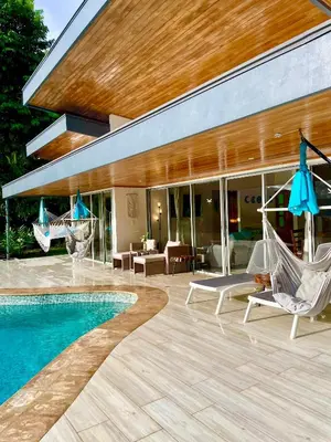 a patio with chairs and a pool and a house at Casa de Teak in Savegre